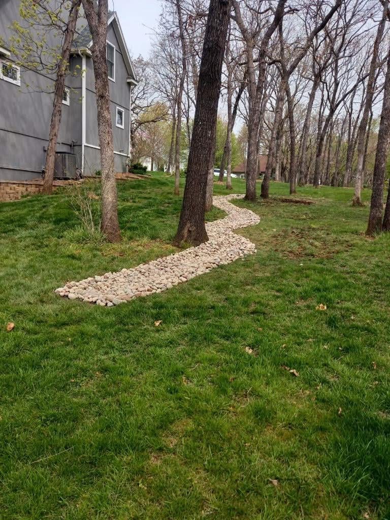Completed river rock French drain beside house