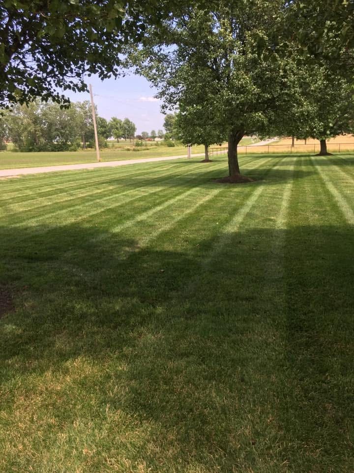 Striped lawn mowing near country road