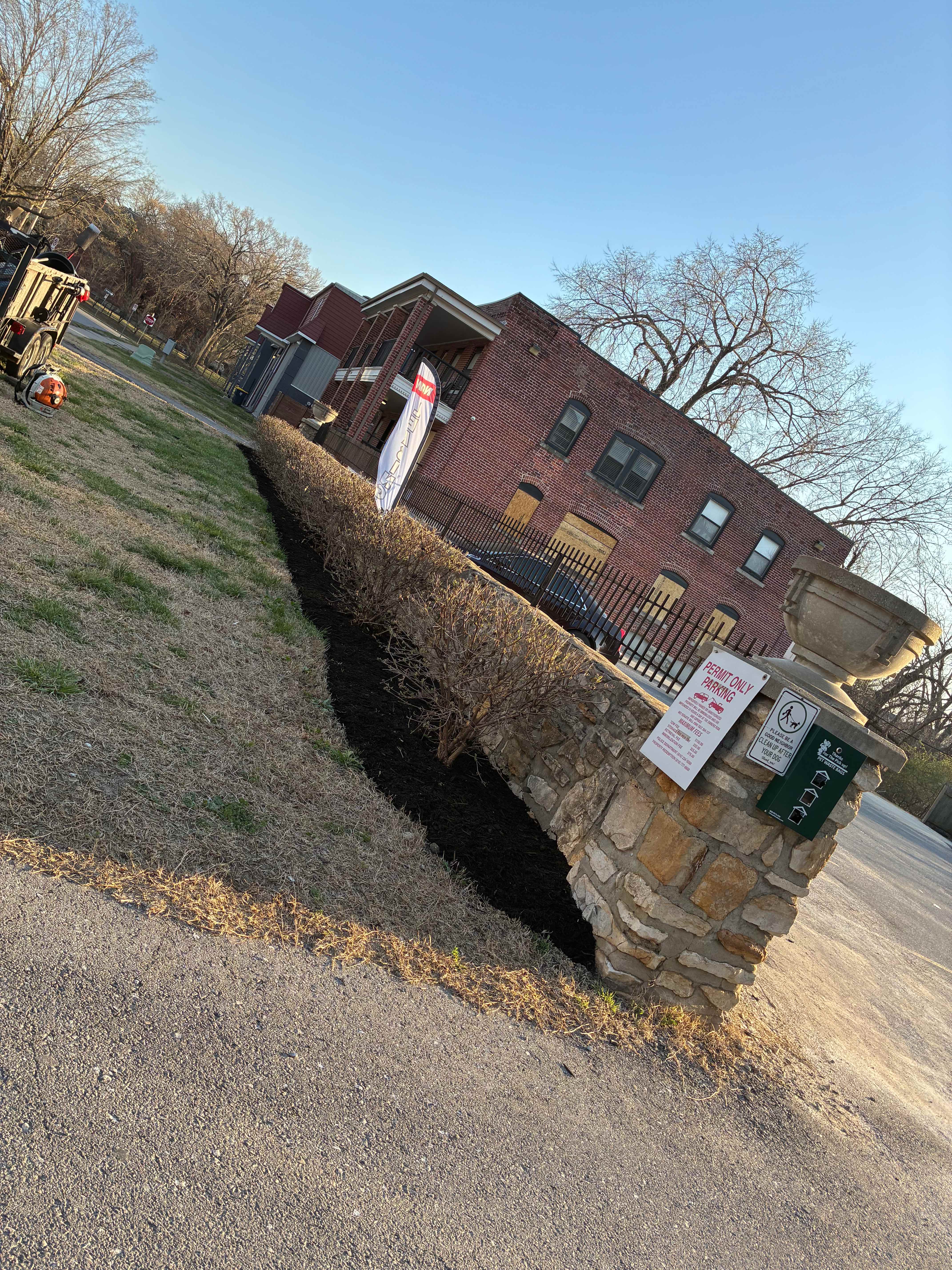 Mulch along stone wall with W Tree Services banner